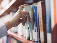 Hand selecting a book from a bookshelf