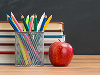 Apple, jar of pencils, stack of books