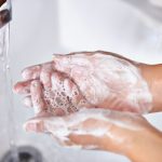 A cropped shot of a young woman washing her hands in her bathroom