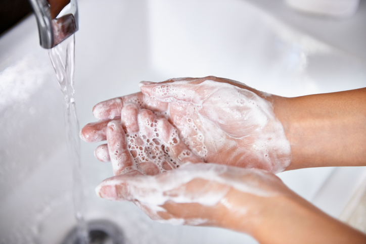 A cropped shot of a young woman washing her hands in her bathroom